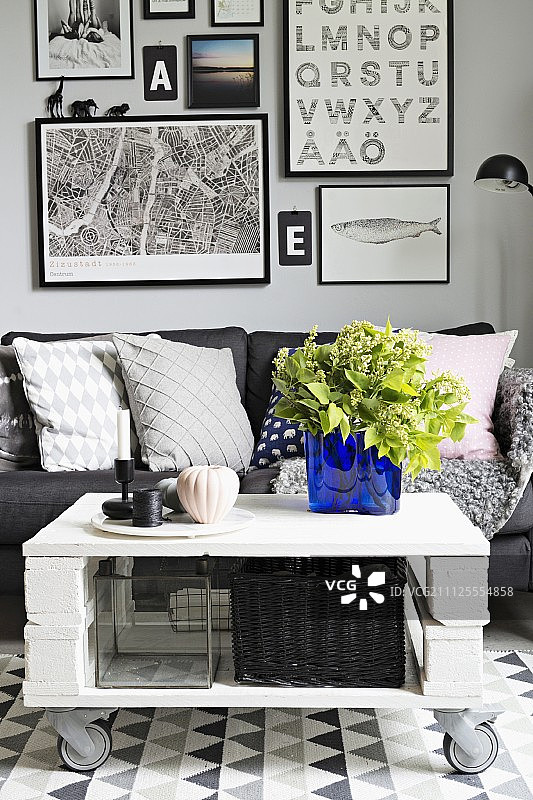 白色灰色沙发休息区，DIY咖啡桌上的宝蓝色玻璃花瓶，背景是照片墙图片素材