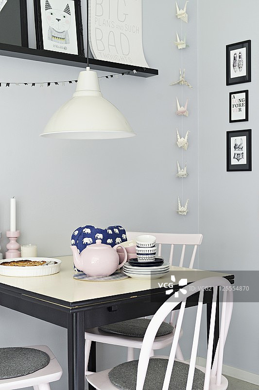 灰色墙壁前的黑白小餐厅，有折纸花环和相框画廊图片素材