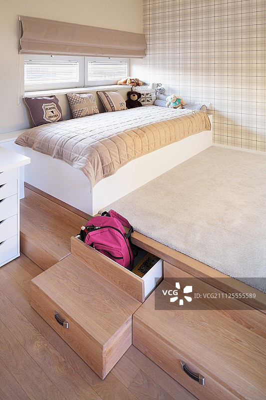 带抽屉的木制台阶平台，儿童床上散落的靠垫和淡格子呢墙纸图片素材