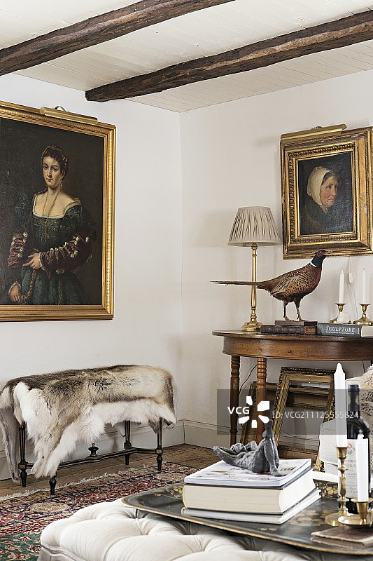 长凳对面脚凳上的烛台，动物皮地毯下方是墙上镀金镶框的女人画像图片素材