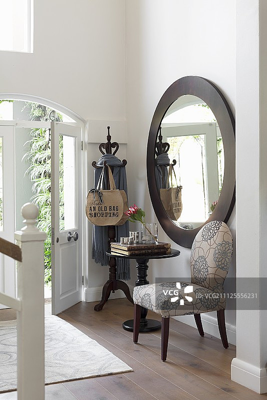 门厅墙上大圆镜下的软垫椅和小酒馆桌子图片素材