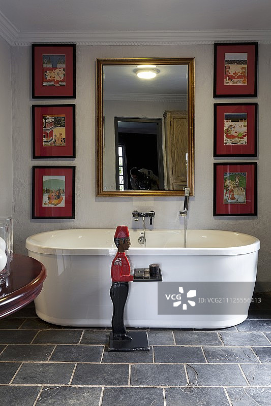 男人雕像、独立浴缸和艺术品装饰的浴室图片素材