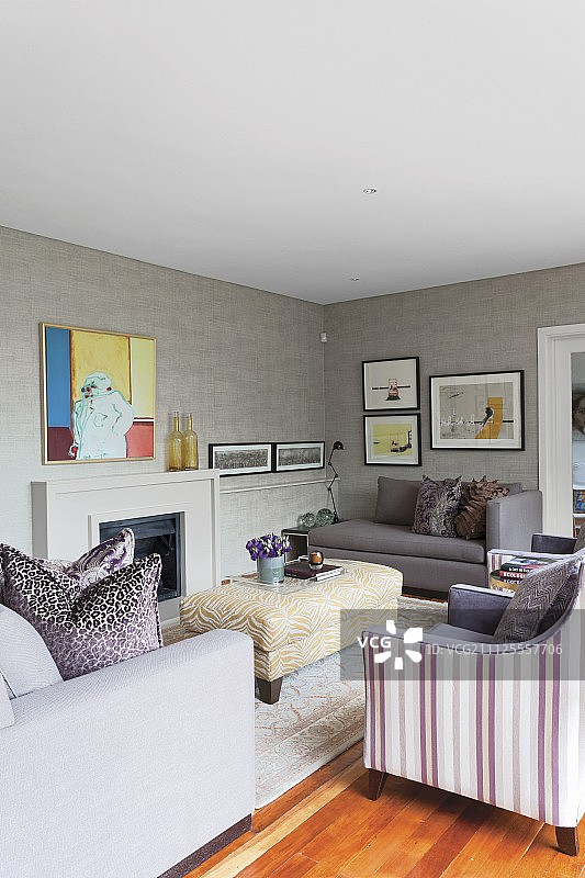 现代环境中，不同面料的扶手椅围绕着开放式壁炉前的 ottoman图片素材