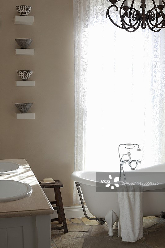 蕾丝窗帘前的独立式复古浴缸图片素材