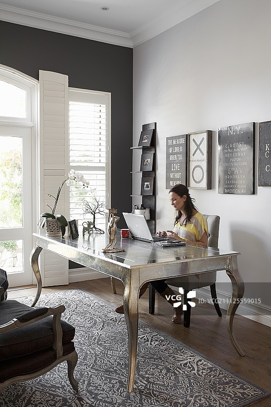 坐在优雅书房的后现代银色桌子旁的女人图片素材