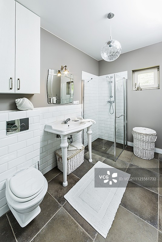 白色和灰色浴室-盥洗台，白色转腿，靠墙半高瓷砖和落地式玻璃淋浴隔间图片素材