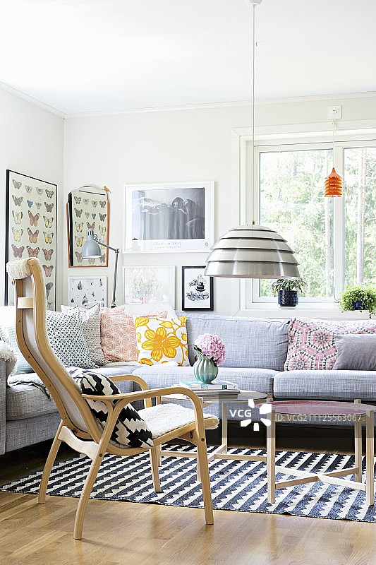 带有复古靠垫的角落沙发和斯堪的纳维亚木制家具的座位区；背景墙上的图片画廊图片素材