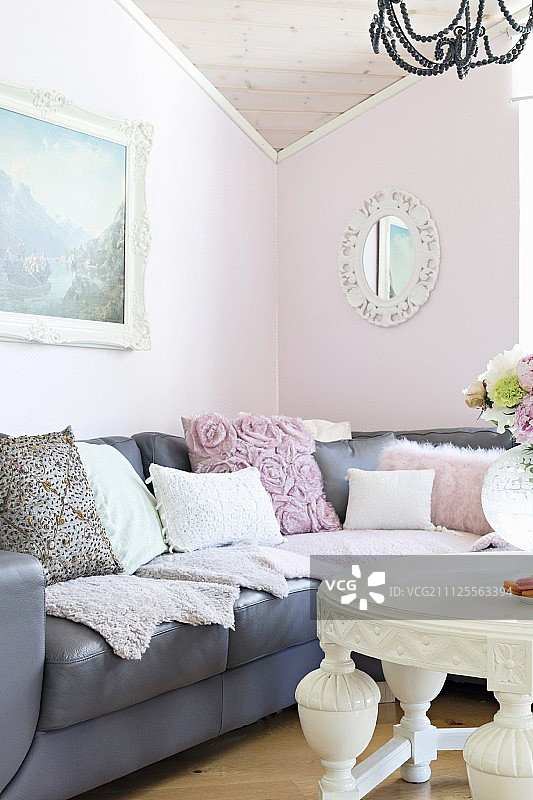 客厅里带有各种靠垫的灰色皮沙发和粉红色墙壁图片素材