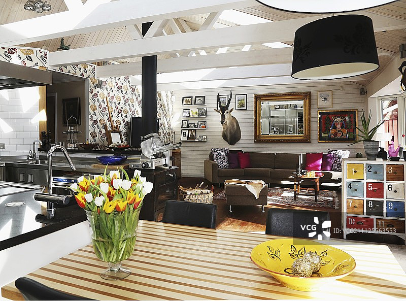 开放式折衷主义组合客厅和厨房，带有外露的木屋顶结构图片素材