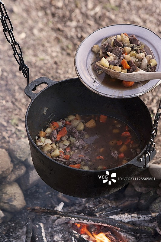肉炖在碗和铁煮锅挂在篝火上图片素材