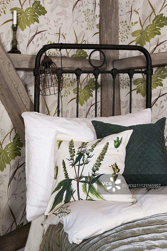 黑色金属床上绿白靠垫，植物图案墙纸背景图片素材