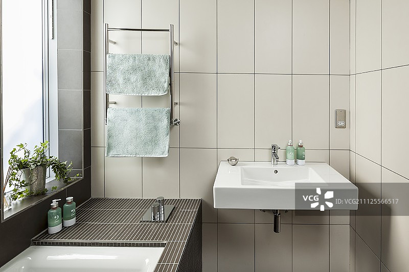 设计师浴室：浴缸旁白色竖版瓷砖墙上的洗手池图片素材