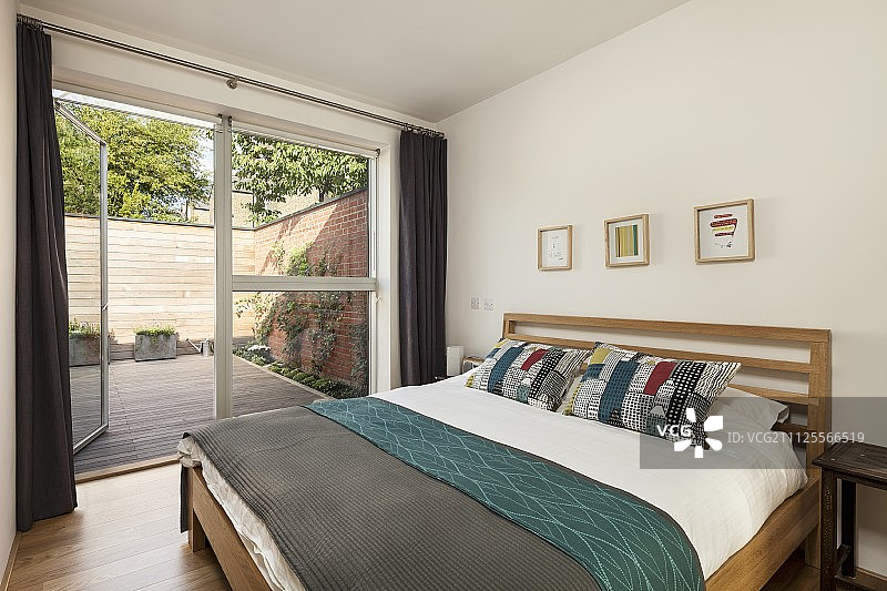 简约卧室：木制框架双人床和玻璃墙露台门图片素材