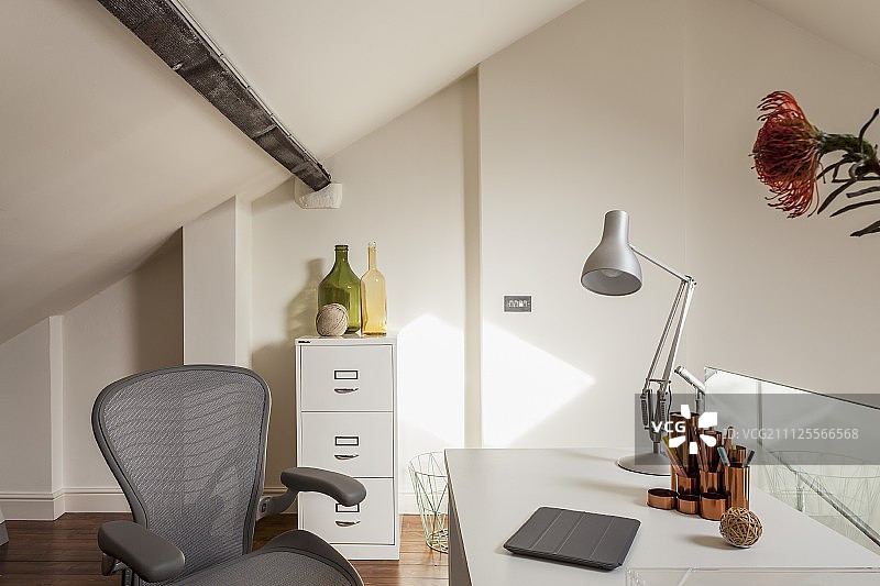 画廊里的家庭办公室：灰色办公椅、书桌、台灯和文件柜图片素材