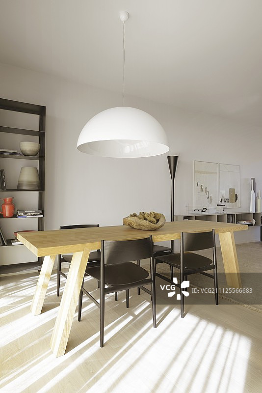 极简室内：浅色实木桌和深色木椅，吊灯在上方，地板有光影图案图片素材