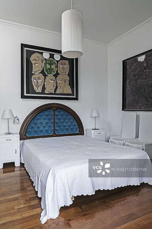 墙上图片下的法式床，带有古董半圆形床头板；前景是带有白色圆柱形织物灯罩的吊灯图片素材