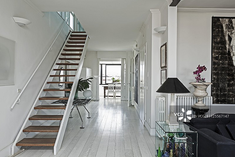 开放式走廊：现代阁楼公寓的楼梯，玻璃边桌上的台灯图片素材