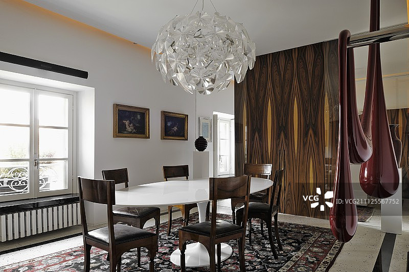 明亮的餐厅，配有白色设计师餐椅、镀金画框油画和现代艺术品图片素材