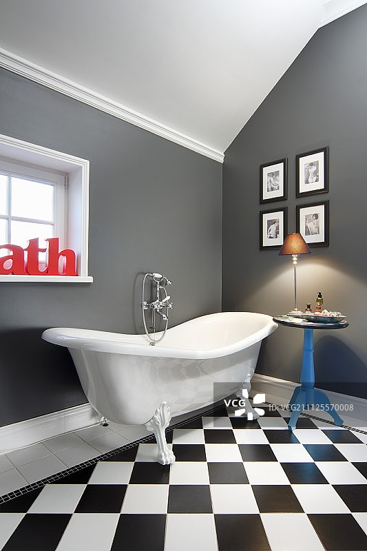 优雅的浴室，爪足浴缸旁有边桌和照片墙图片素材