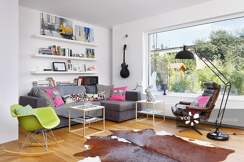 开放式室内全景窗前的绿色经典摇椅、转角沙发和皮革扶手椅图片素材