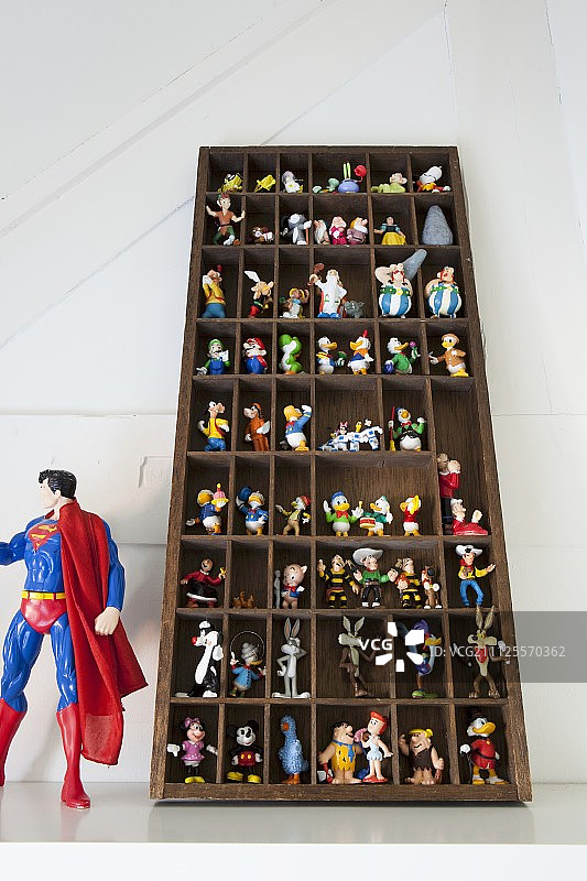 陈列柜中色彩缤纷的漫画人物模型，旁边是较大的超人玩偶图片素材