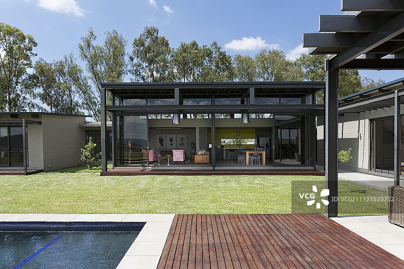 从带游泳池的露台看到的建筑师设计的房屋的开放式内景图片素材