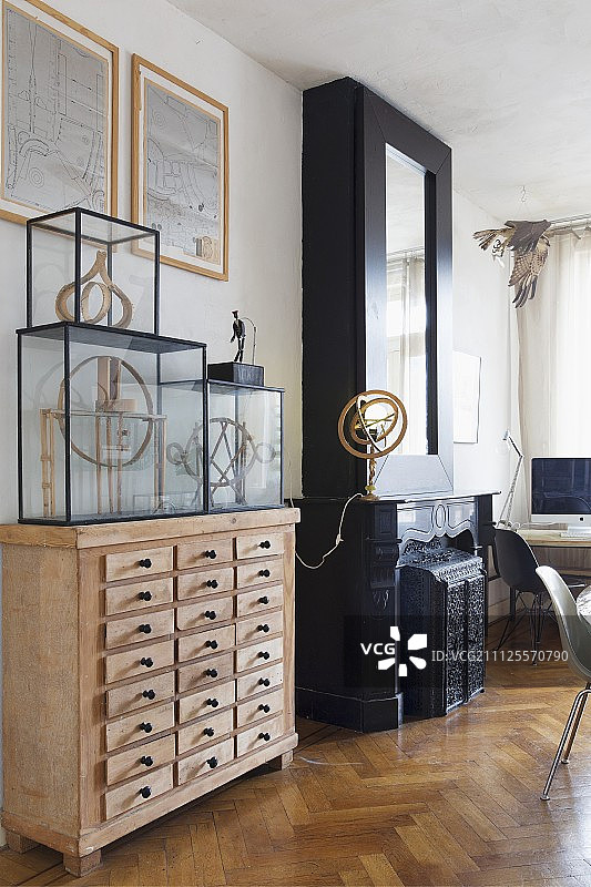 木制药柜顶部的玻璃展示柜，旁边是黑色壁炉和古董天文仪台灯图片素材