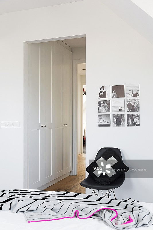 条纹床罩、靠垫、黑色贝壳椅和嵌入式衣柜图片素材