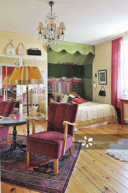 绿色调女性卧室：复古红色扶手椅、边桌、落地灯和双人床图片素材