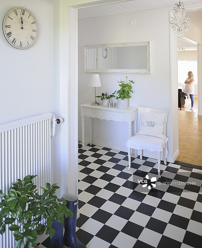 开放式走廊，带方格地板、白色椅子和靠墙的控制台图片素材