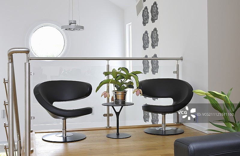 黑色设计师休闲椅和玻璃栏杆楼梯边的边桌图片素材
