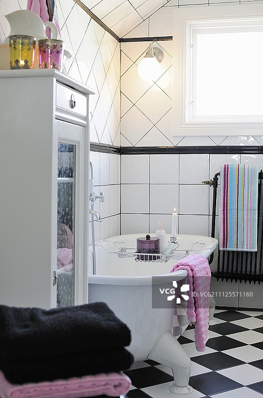 黑白乡村风格浴室，浴缸架上放着点燃的蜡烛的独立式浴缸图片素材