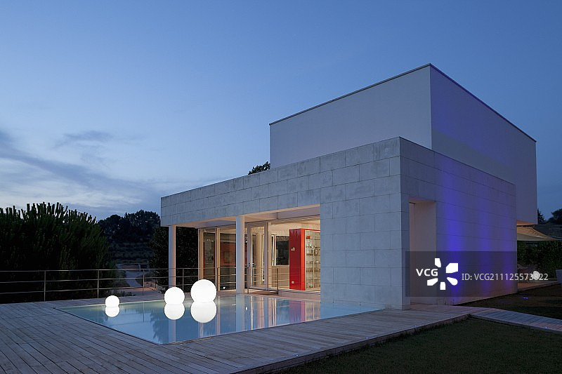 黄昏氛围：当代住宅外的泳池、球形落地灯和木制甲板图片素材