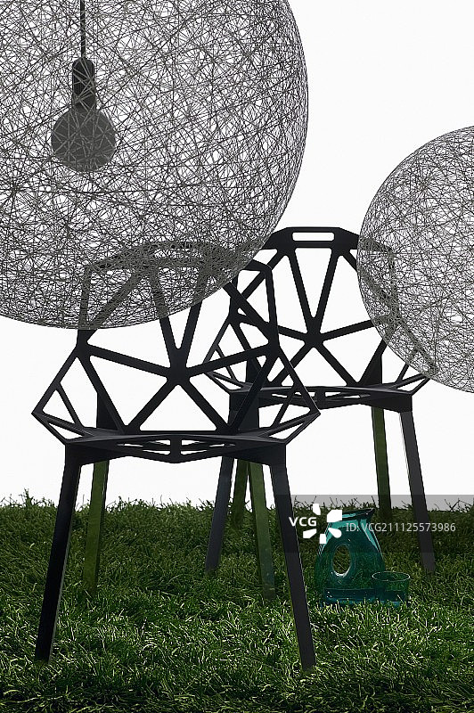 草坪上的球形吊灯与带六边形支架的设计师椅子图片素材