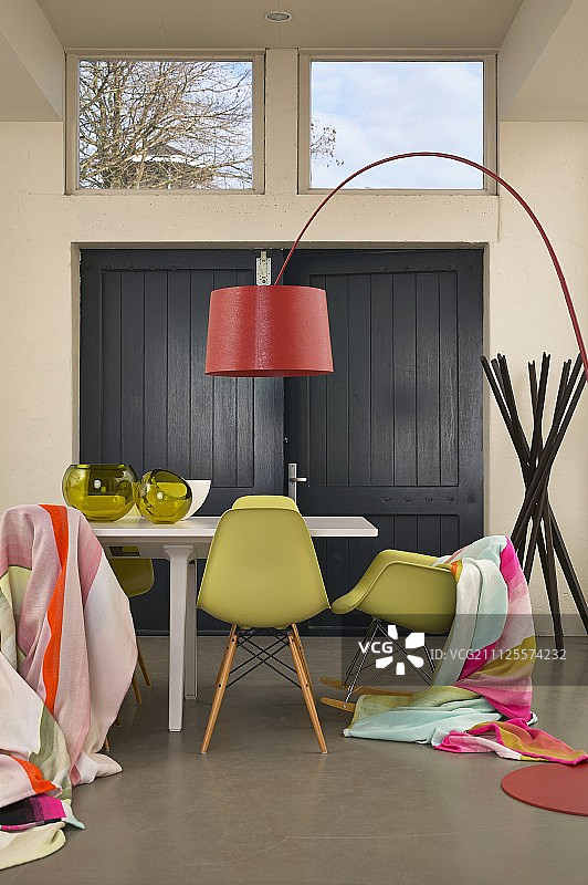 餐桌、经典椅子上的毯子和红色弧形落地灯图片素材