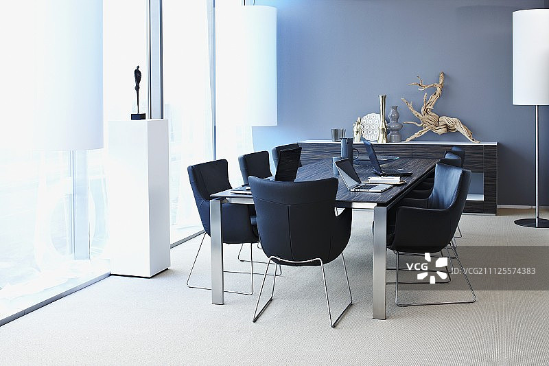 现代会议室里围绕着桌子的金属框架黑色扶手椅图片素材