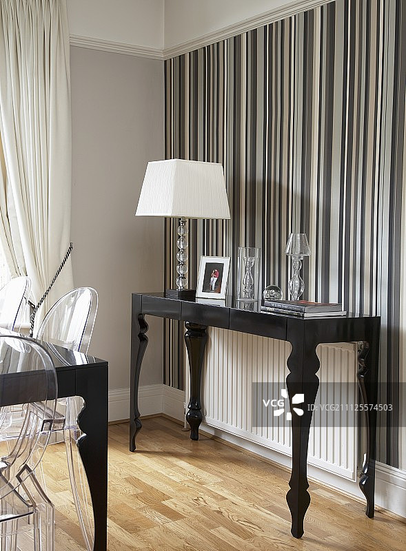 后现代黑色控制台桌和台灯，白色灯罩，背景墙是各种灰色条纹壁纸图片素材