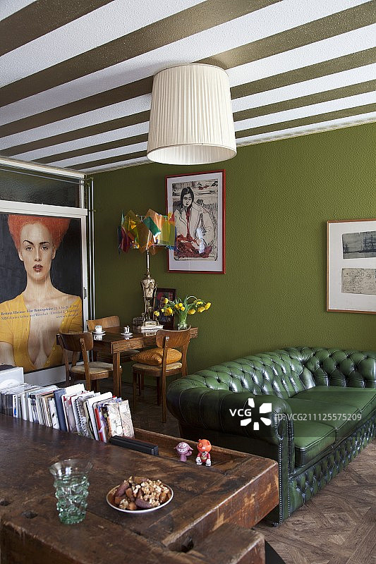 绿色切斯特菲尔德沙发、绿色背景墙和绿白条纹天花板图片素材