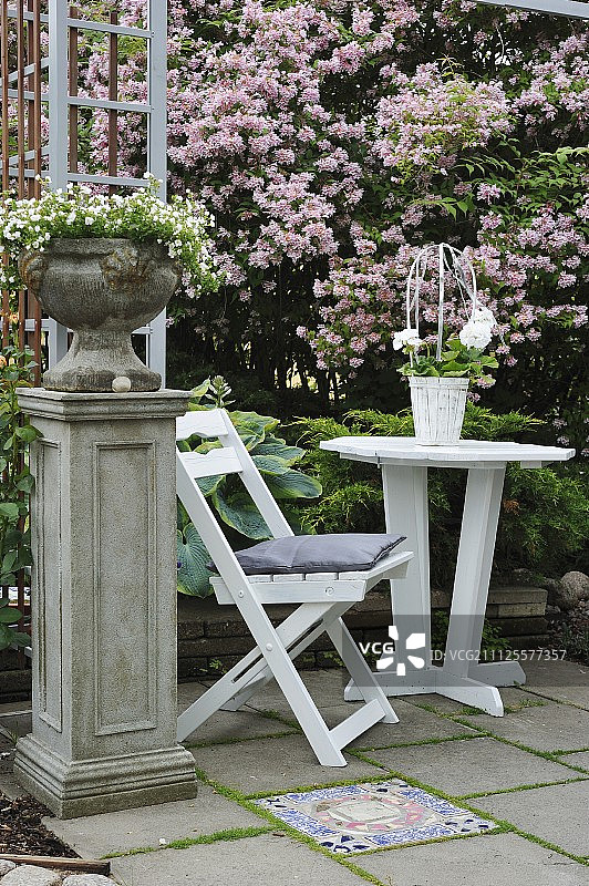 白色花园椅和露台桌子旁边的壁炉台上的花盆图片素材