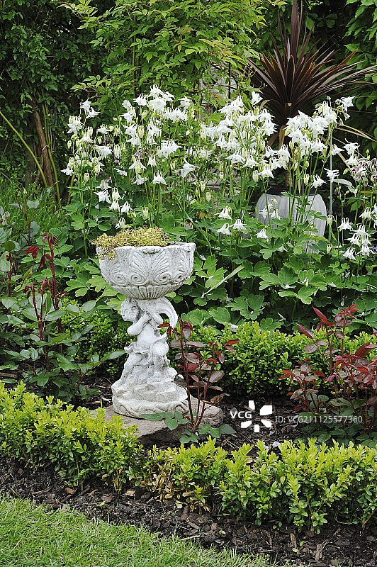 花园中天使雕像支撑的花盆图片素材