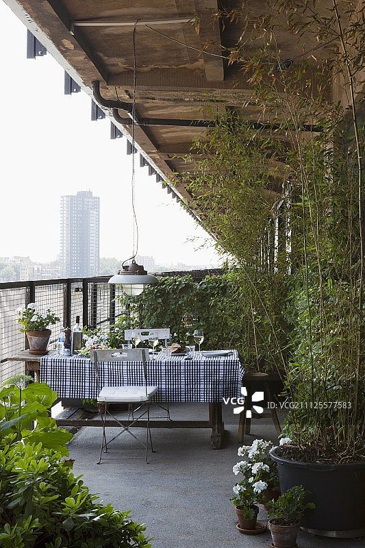 带有黑白格纹桌布和盆栽的阳台桌子，可欣赏城市景观图片素材