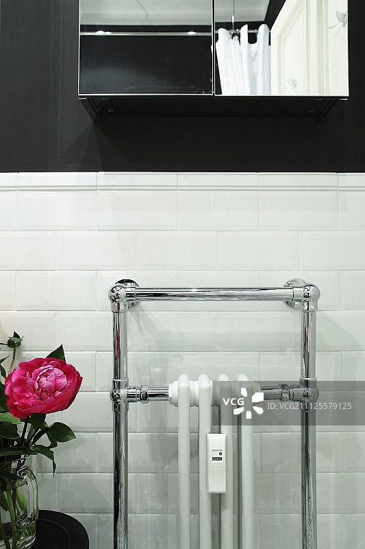 白色瓷砖浴室墙壁上的散热器和毛巾架图片素材