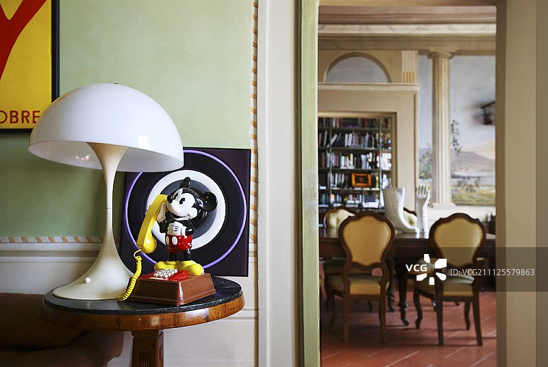 米奇老鼠雕像和老式台灯在边桌上；可看到墙上有错视画的餐厅图片素材