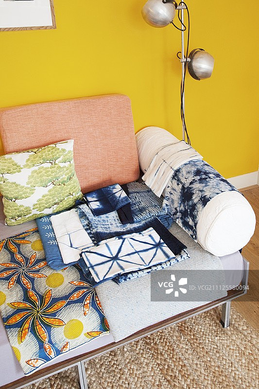 沙发上带有靠垫的蜡染面料，背景为黄色墙壁图片素材
