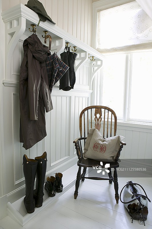 白色镶板衣帽间的温莎椅与靠垫；高筒靴、雨衣和雨伞图片素材