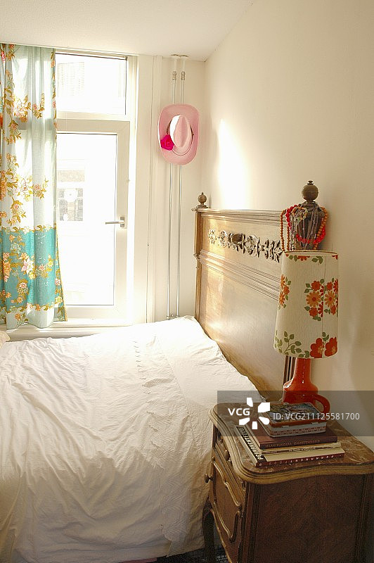 复古台灯位于古董床头柜上，床边是雕花床头板的小卧室图片素材