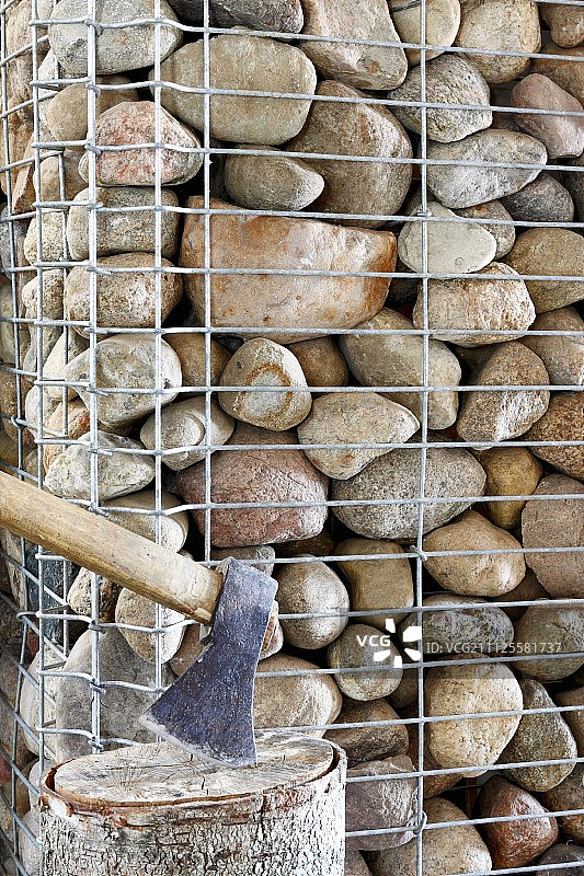 斧头插在石笼墙前的砧板上图片素材