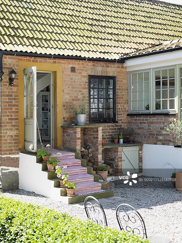 阳光下的砖房，前门打开，台阶上铺着地毯图片素材