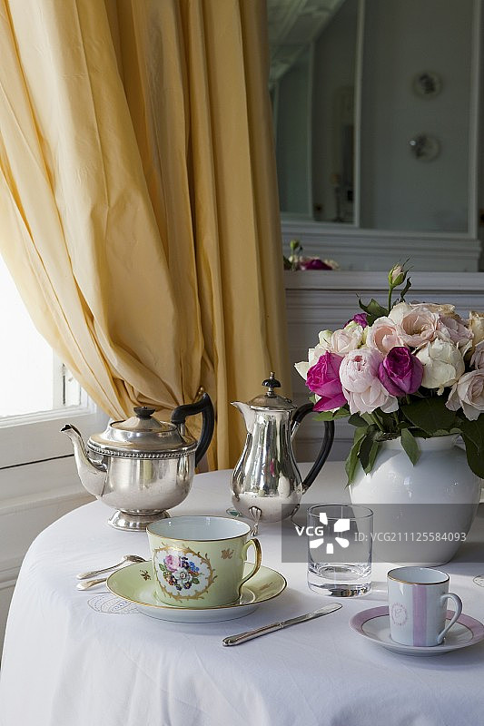 杯子、花瓶、银茶壶和咖啡壶摆放在圆桌上图片素材