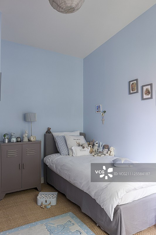 儿童卧室：灰色床裙和白色床单的单人床，旁边是复古金属柜图片素材